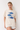 Woman wearing a cream t-shirt with blue fish graphics on a white background