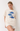 Woman wearing a cream-colored t-shirt with blue fish designs and floral shorts on a white background