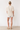 Person wearing a beige t-shirt and patterned shorts standing against a white background