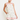Woman wearing a white dress with floral embroidery and red trim on a plain background