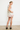 Woman wearing a white dress with red trim against a plain background