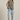 Woman wearing a black and white checkered top and light blue jeans against a beige background