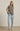 Woman wearing a black and white checkered top and light blue jeans against a beige background