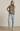 Woman wearing a checkered top and light blue jeans against a plain background