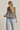 Woman wearing a checkered sleeveless top and light blue jeans on a beige background