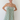 Woman wearing a green and white striped dress against a white background