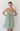 Woman wearing a green and white striped dress against a white background