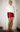 Woman wearing a red skort with a tonal bow print.