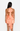 Woman wearing a peach-colored dress with a halter neck and open back on a white background