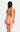 Woman wearing a peach-colored dress with a bow detail on a white background