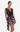 A woman modeling a sleeveless navy wrap-style mini dress with a draped neckline and a colorful floral print, set against a plain white studio background.