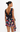 A woman shown from the back wearing a sleeveless wrap-style dress with a draped open back and a multicolor floral print on a black base, photographed against a plain light background.