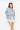 A woman modeling a light blue knit cardigan over a matching light blue satin slip dress with white lace trim, photographed against a plain white studio background.