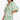 Woman wearing a green and white patterned dress on a white background