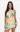 Woman wearing a sleeveless dress with palm tree and sunset design on a plain background