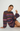 A woman wearing a long-sleeve knit sweater dress with horizontal stripes in purple, pink, orange, and blue, posing against a light gray studio background.