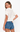 Woman wearing a white blouse with lace details and blue denim shorts on a white background