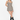 A woman modeling a sleeveless mini dress with a brown, beige, and black gingham pattern, paired with black knee-high boots, against a plain white studio background.
