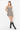 A woman modeling a sleeveless mini dress with a brown, beige, and black gingham pattern, paired with black knee-high boots, against a plain white studio background.