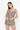 A woman modeling a sleeveless romper with a brown, beige, and black gingham pattern against a plain white studio background.