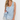 A woman modeling a light blue satin sleepwear set with white lace trim, consisting of a sleeveless button-front top and matching shorts, against a plain white studio background.