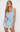 A woman modeling a light blue satin sleepwear set with white lace trim, consisting of a sleeveless button-front top and matching shorts, against a plain white studio background.