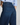 Close-up back view of a person wearing dark blue denim jeans with a light blue and white striped shirt, showing the back pockets and waistband details.