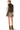A woman shown from the back wearing an olive green faux fur vest over a cream long-sleeve top, a beige and brown plaid pleated skirt, and brown suede ankle boots, against a plain white background.