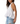 Woman wearing a white sleeveless top and ripped jeans on a white background