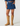 Person wearing a blue denim skirt and tan knee-high boots on a white background