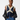 A model wearing a navy blue satin top with cream lace trim, styled with a black leather jacket and blue jeans against a plain white background.