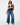 A woman modeling a sleeveless navy top with cream lace trim and wide-leg blue jeans against a plain white studio background.