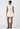 Person wearing a white sleeveless dress and brown boots on a white background