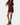 A woman modeling a short-sleeve mini dress in a deep plum purple color with a keyhole cutout at the collar, paired with brown ankle boots, against a plain light gray background.