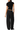 A model shown from the back wearing a black draped short-sleeve crop top and wide-leg black pants against a plain white background.