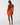 Woman wearing an orange dress with thin straps on a white background