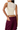 A woman shown from the back wearing a sleeveless cream mesh and knit crop top with a sheer back panel, paired with dark purple cargo pants, against a plain white background.