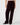 A person wearing high-waisted, wide-leg velvet pants in a deep burgundy color, paired with black pointed-toe flats, against a light gray studio background.