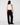 A model shown from the back wearing a white sleeveless top and dark burgundy velvet wide-leg trousers against a light gray studio background.