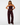 A model wearing a matching dark burgundy velvet two-piece set consisting of a strapless peplum-style top and wide-leg pants, photographed against a solid light gray background.