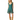 A woman modeling a teal green sleeveless dress with a white polka dot pattern and a floral print hem, paired with tan knee-high boots, against a plain white background.