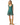 A woman modeling a teal green sleeveless dress with a white polka dot pattern and a floral print hem, paired with tan knee-high boots, against a plain white background.
