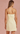 Woman wearing a light yellow dress with thin straps on a pink background
