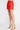 Person wearing a red skirt and beige high-heeled sandals on a white background