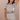 Woman wearing a patterned two-piece outfit against a beige wall.