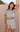Woman wearing a patterned two-piece outfit against a beige wall.