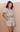 Woman wearing a patterned two-piece outfit against a beige background