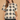 A woman modeling a short-sleeve crochet knit top with a black and beige geometric diamond pattern, lace-up keyhole neckline, and ruffled trim, paired with black shorts against a textured beige background.