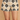 A close-up of a model wearing high-waisted crochet shorts with a black and beige geometric pattern, set against a warm beige textured background.