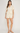 Woman wearing a cream-colored outfit with a white background